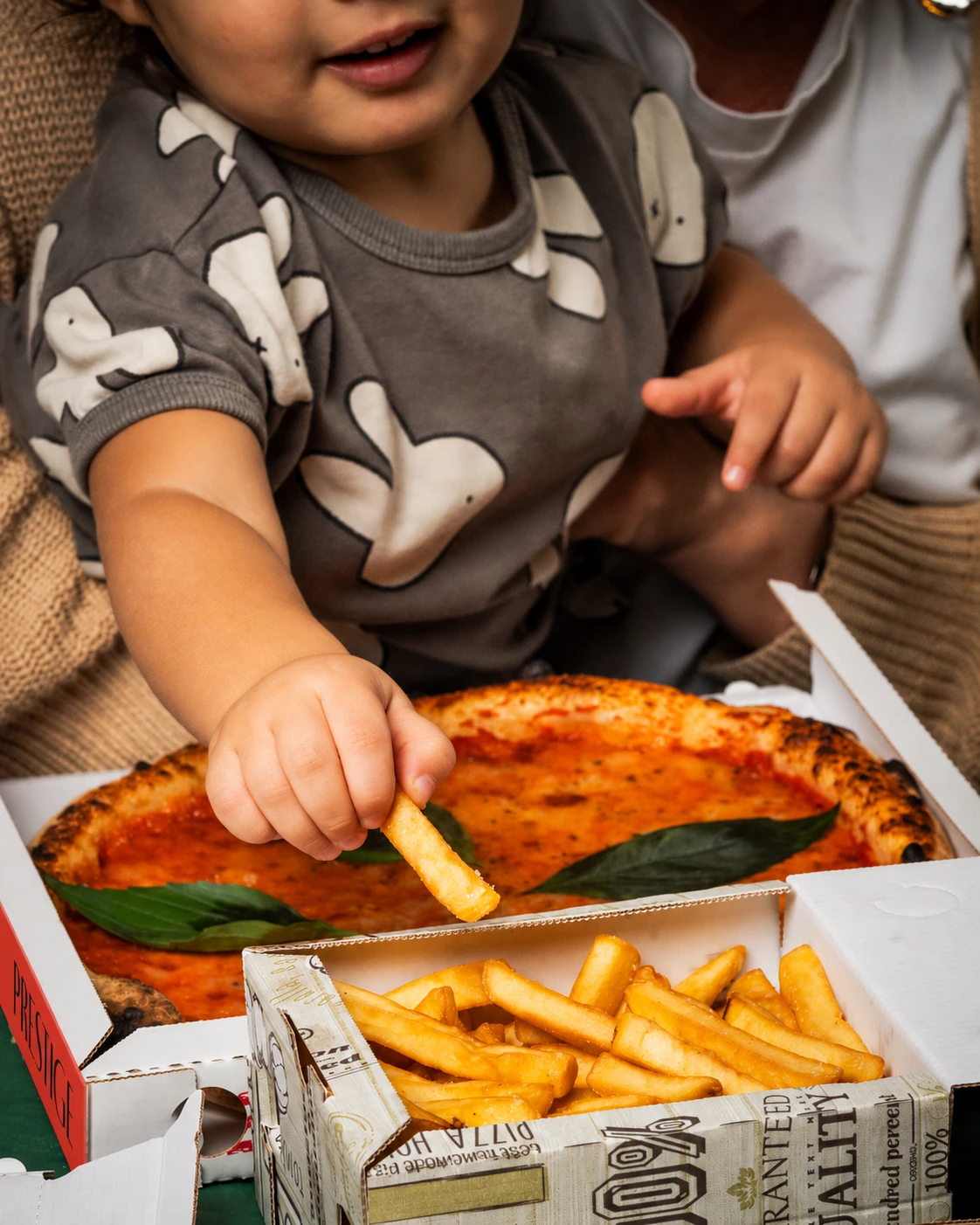 Un bambino prende una patatina accanto alla margherita