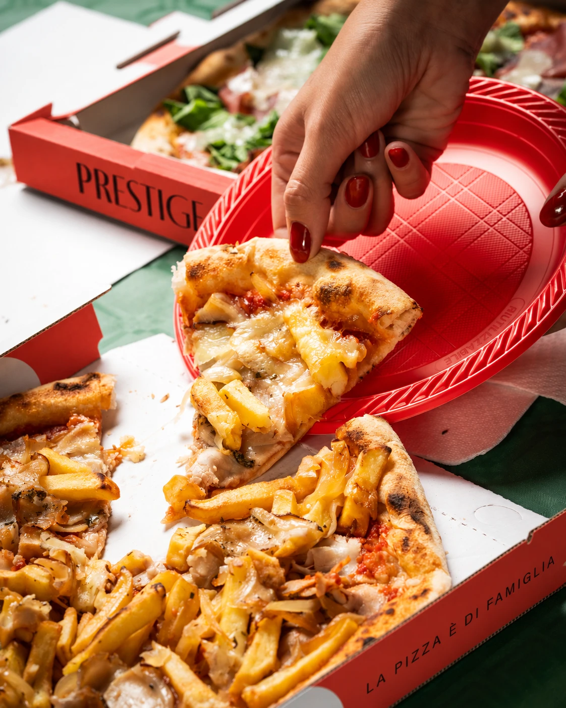 Una fetta di pizza con patatine viene servita su un piatto rosso